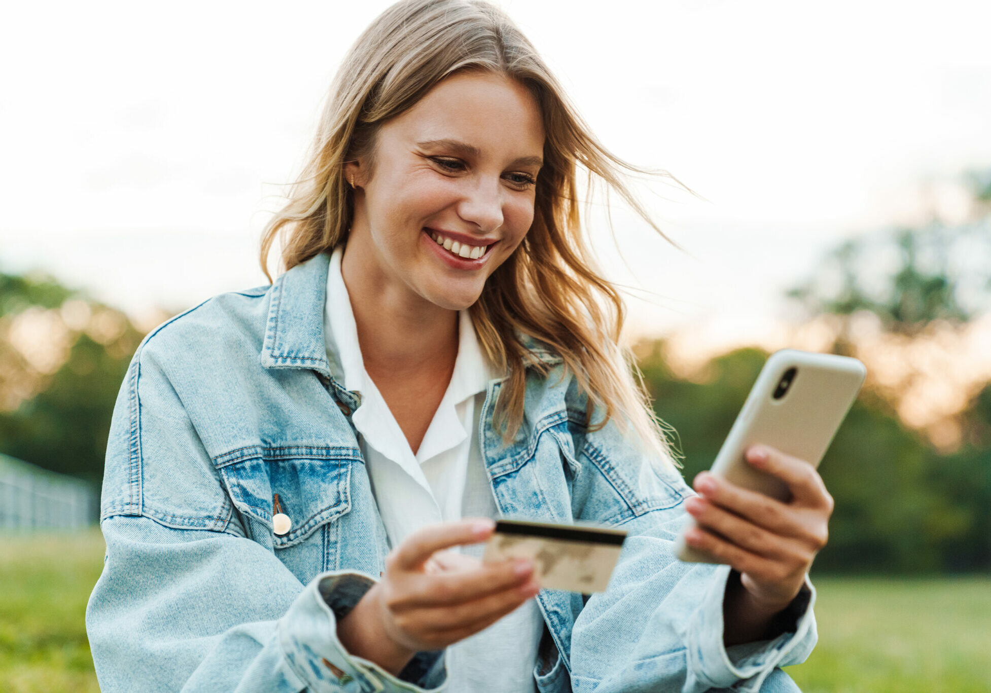 happy-woman-holding-credit-card-and-mobile-phone-w-SAK2JTX